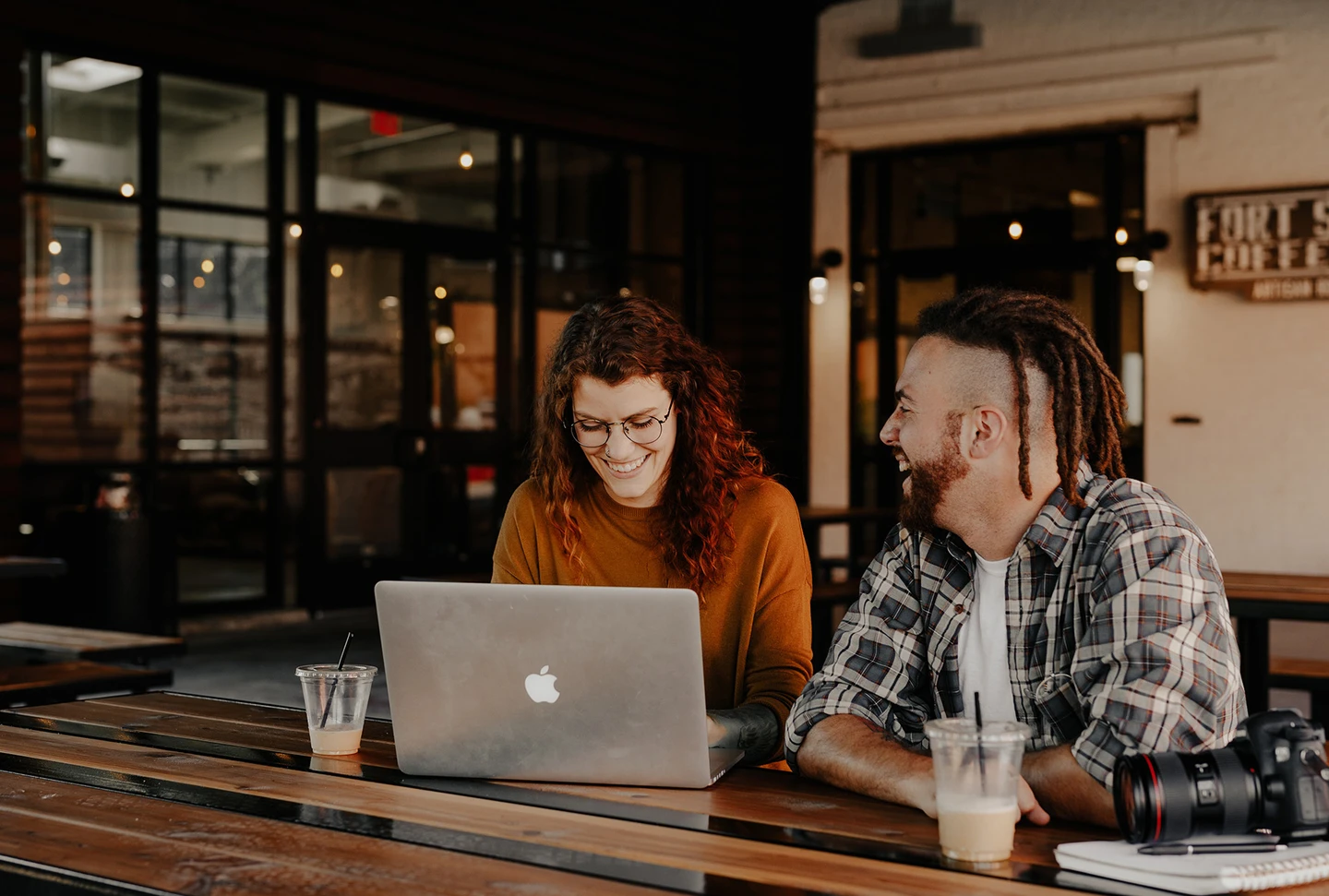 Woman and man in coffee shop sit in front of woman's laptop