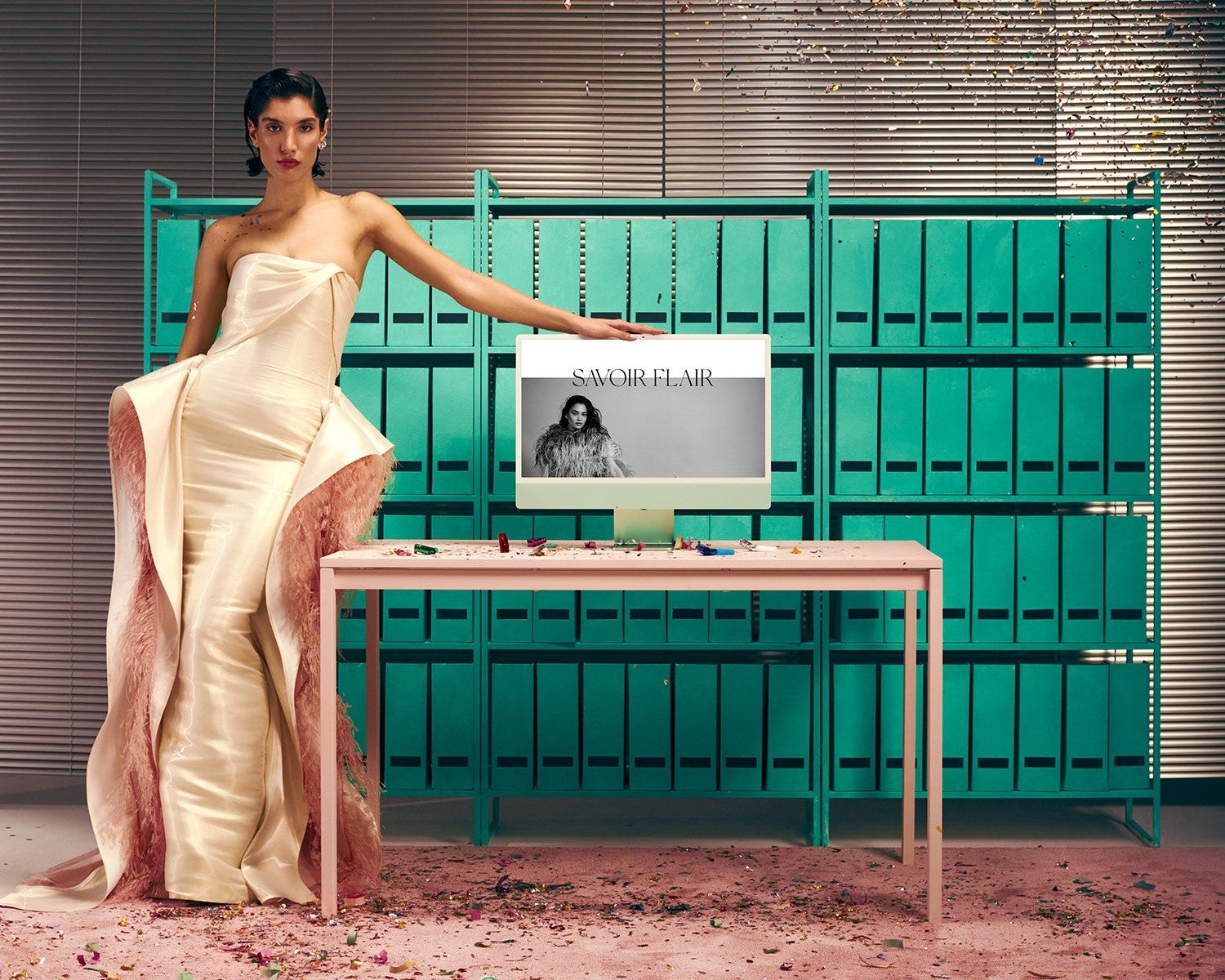 A well-dressed woman standing next to a table with a computer on it