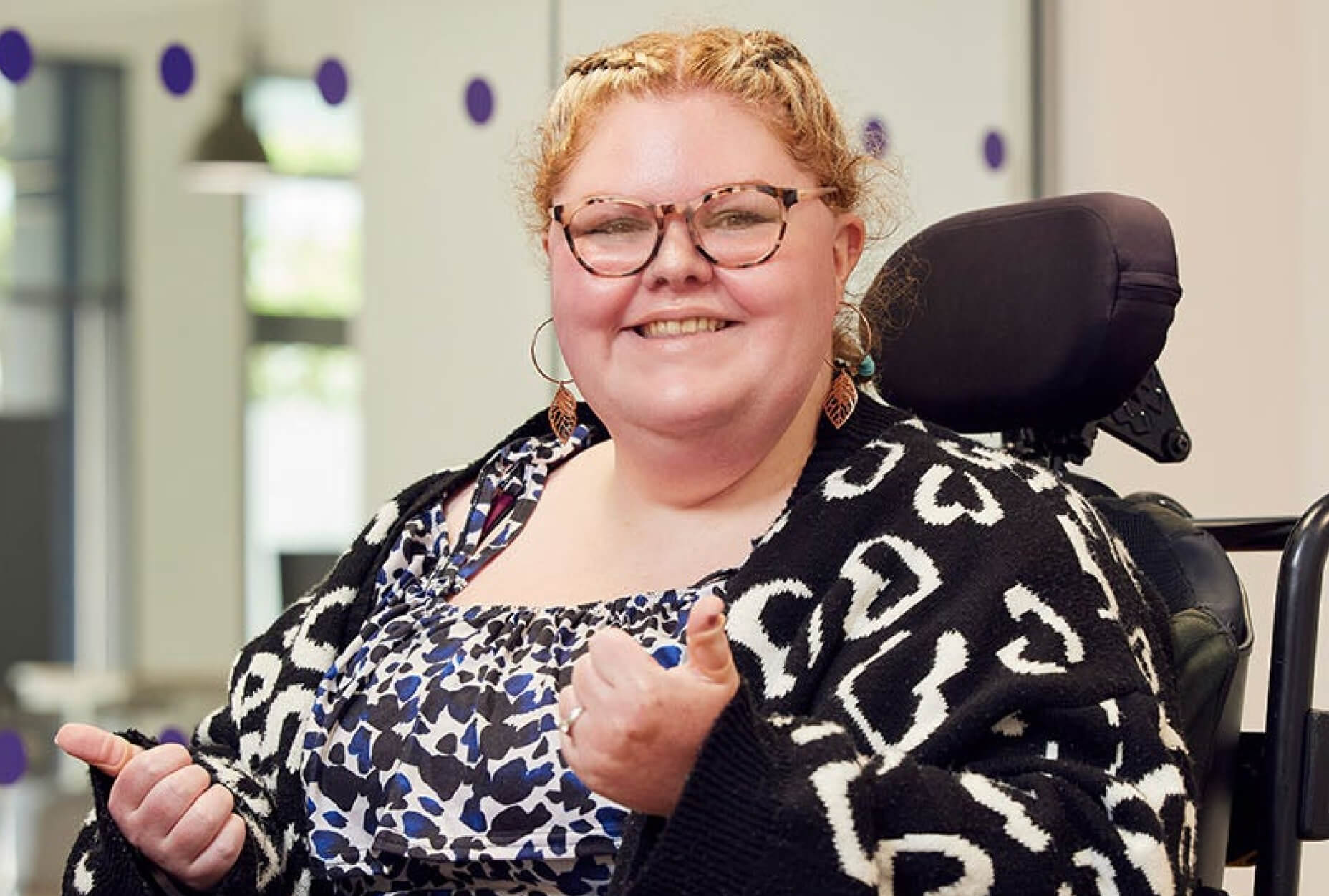 A woman in a wheelchair giving a thumbs up