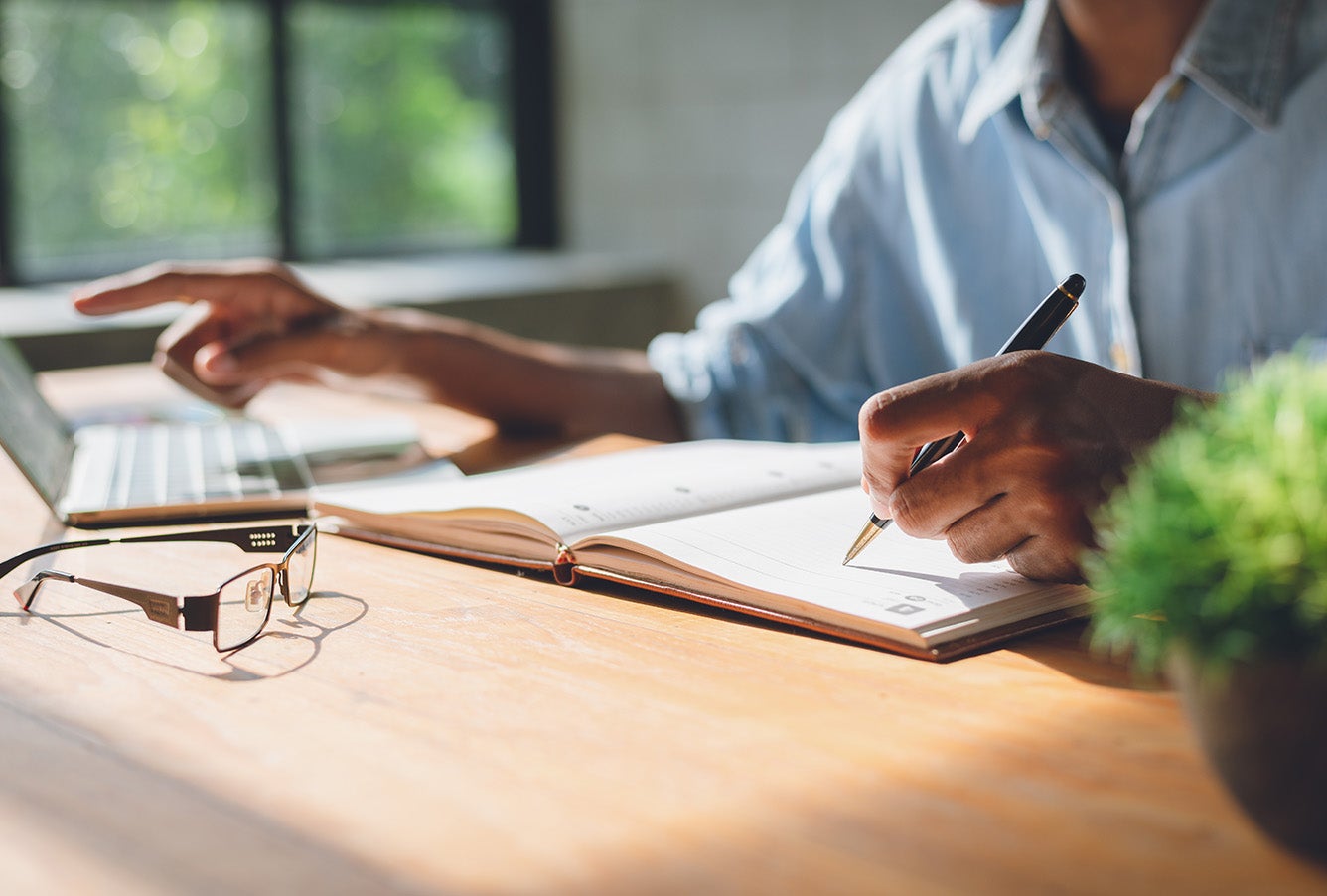 A person preparing a keyword list in their notebook