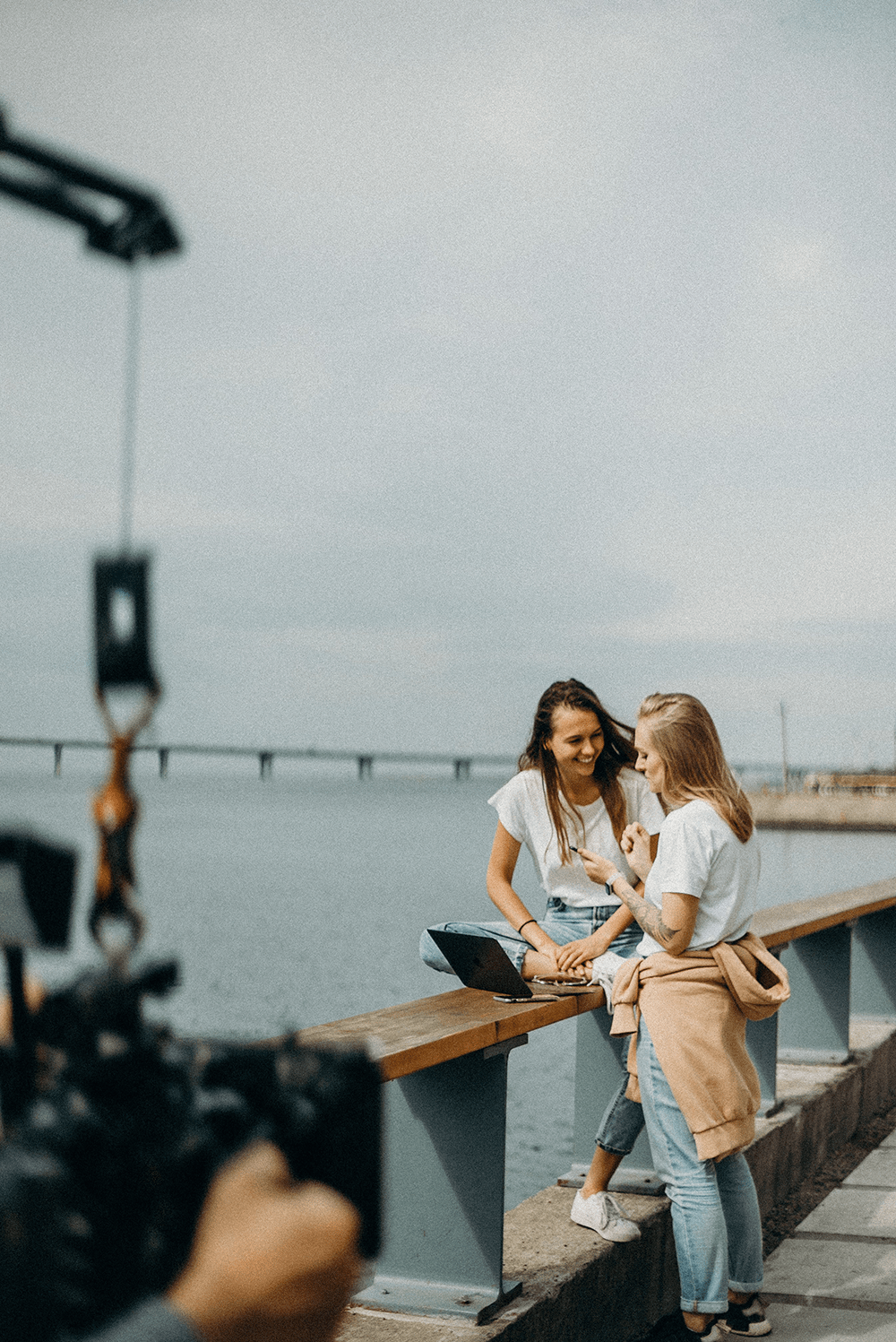 Two girls on a bridge creating content with a laptop and camera