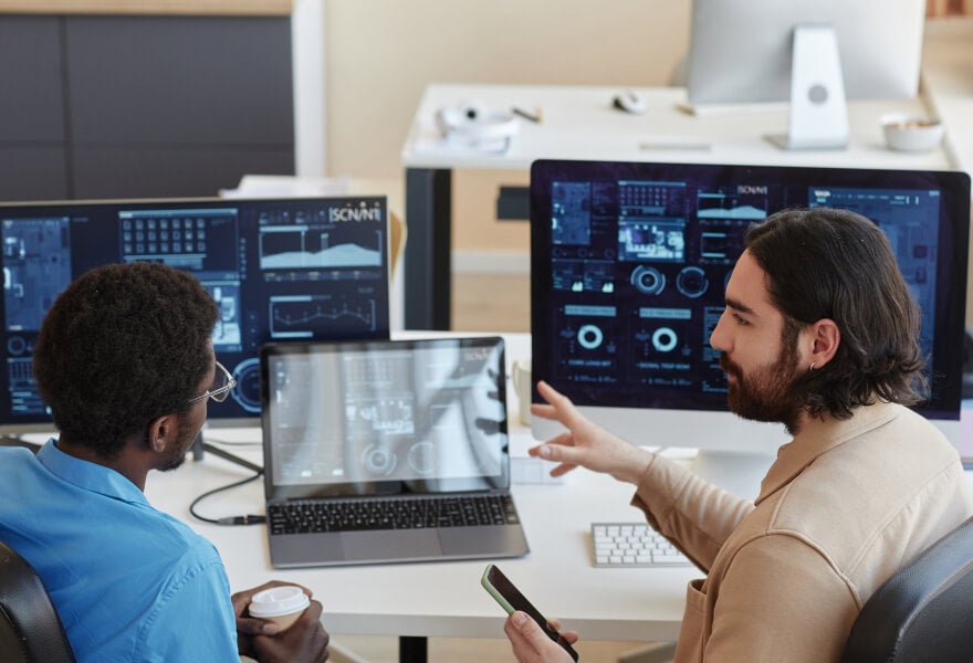 A group of men sitting at a desk with computers