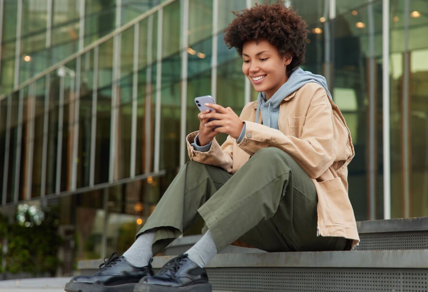 Woman sitting on stairs outside and looking at her phone