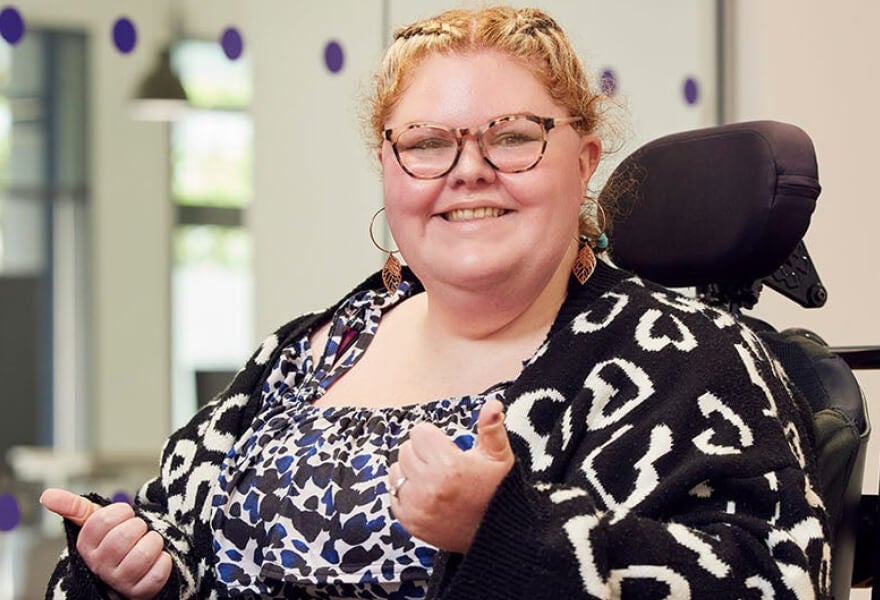 A woman in a wheelchair giving a thumbs up