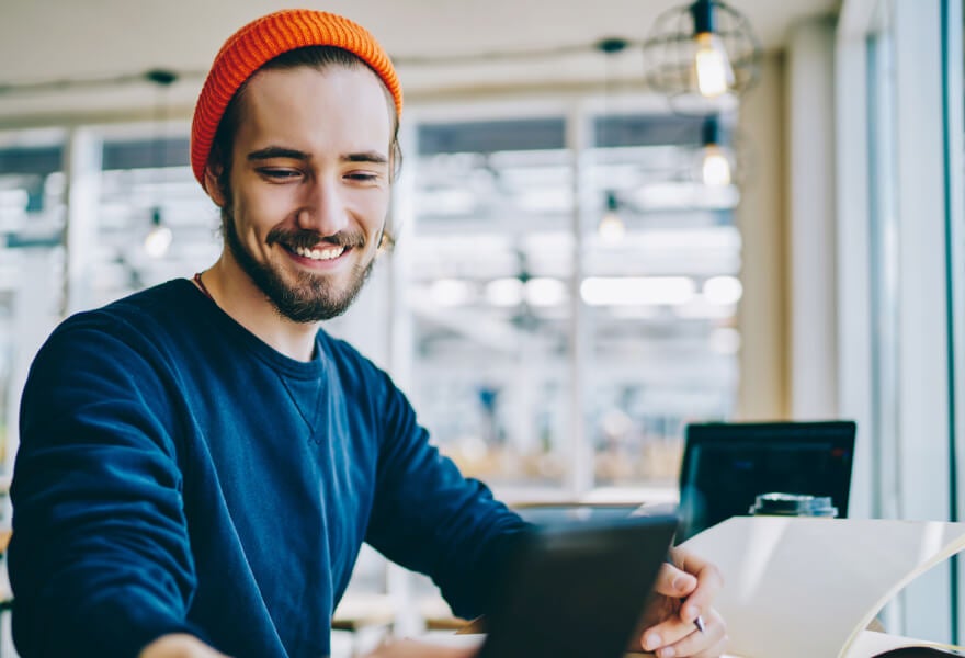 A young man with a beanie smiling and working