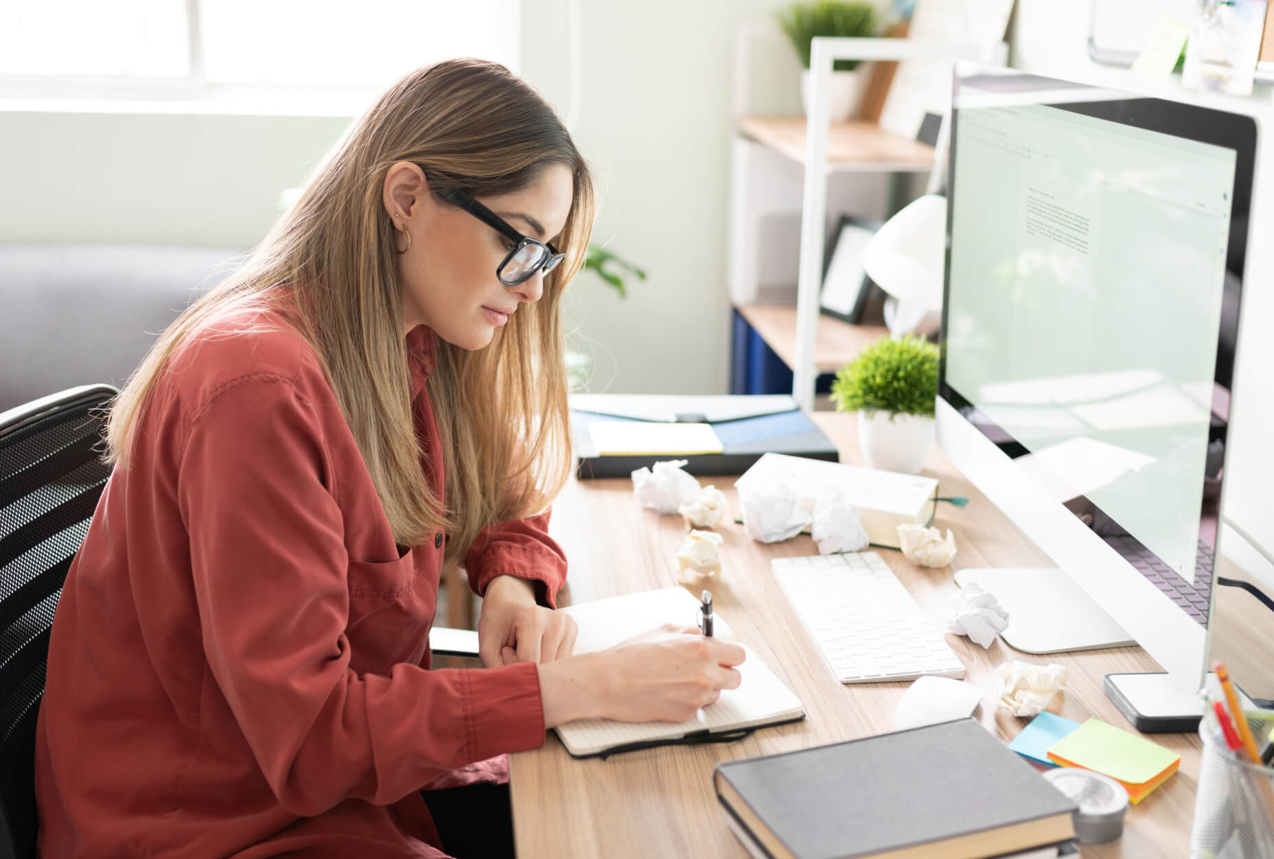 A woman sitting at a desk writing on a notebook