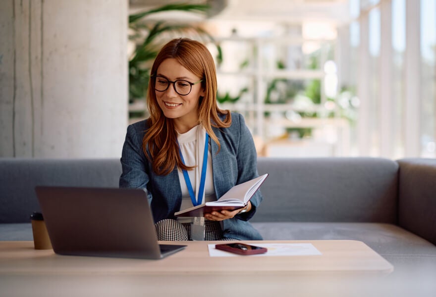 A woman sitting at a table with a laptop and a book
