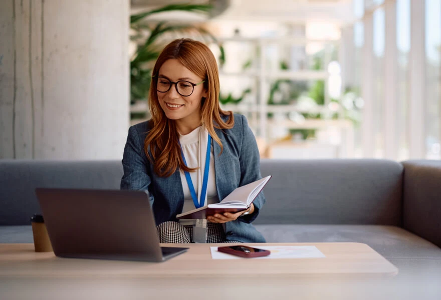 A woman sitting at a table with a laptop and a book