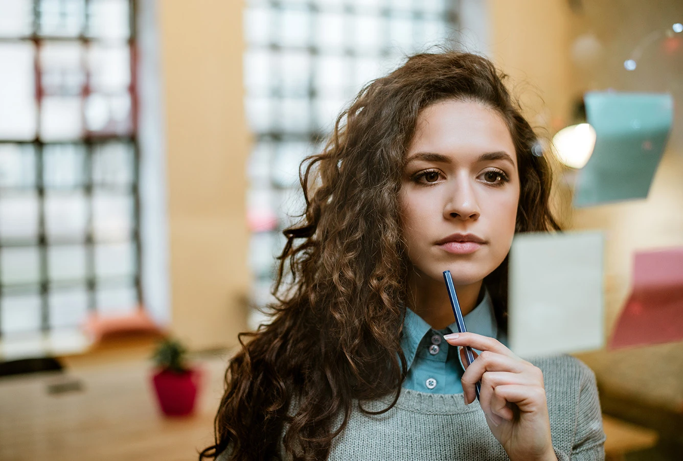 A young woman thinking and looking at sticky notes