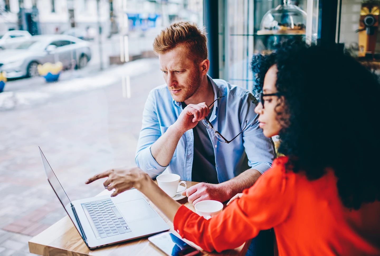 A man and woman sitting at a table looking at a laptop