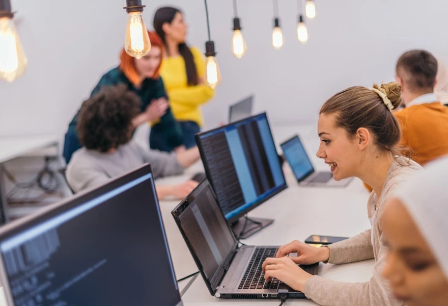 Developers working at laptops in an open office setting.