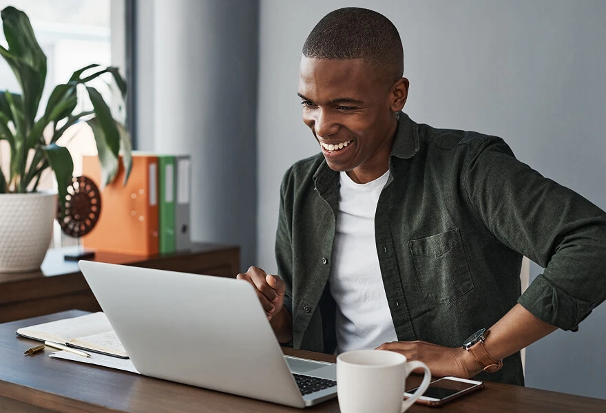 A man smiling and working on his laptop