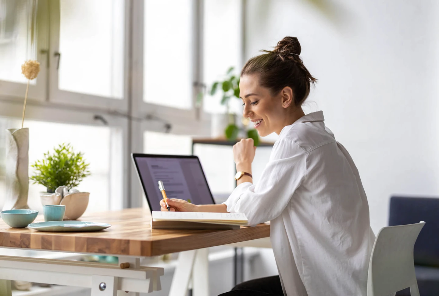 A woman sitting at a table with a laptop and a notebook