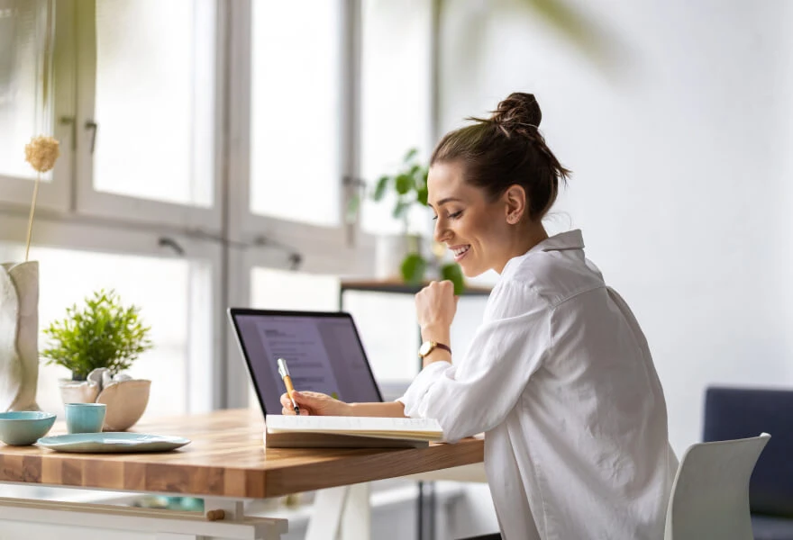 A woman sitting at a table with a laptop and a notebook