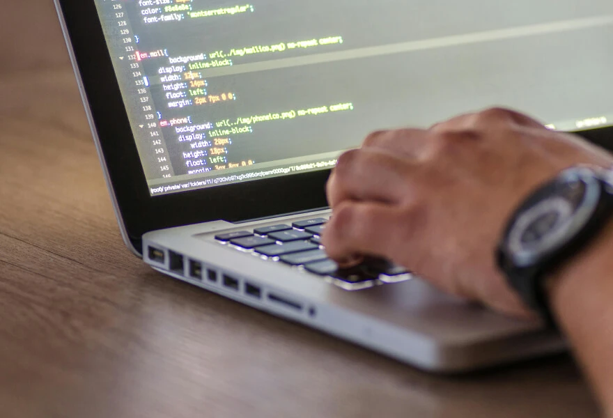 A hand coding on a laptop