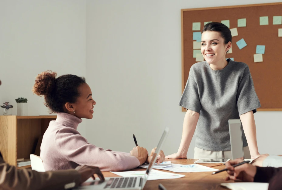 A business woman smiling and standing in front of a group of people