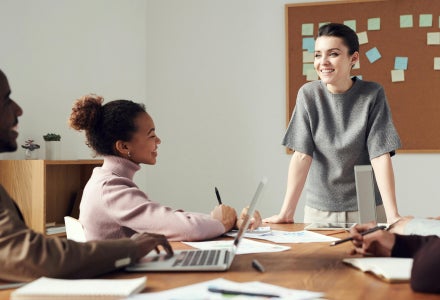 A business woman smiling and standing in front of a group of people