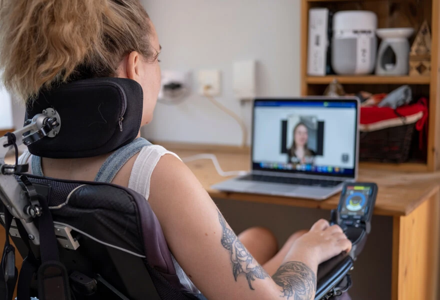 A woman sitting in a wheelchair and using a screen reader