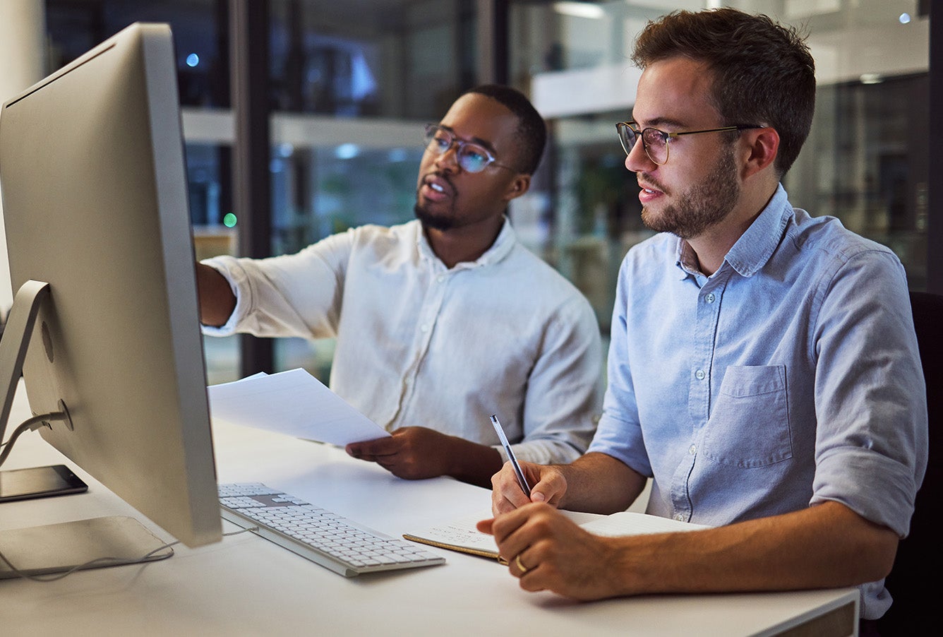 Two young men looking at data on a computer screen