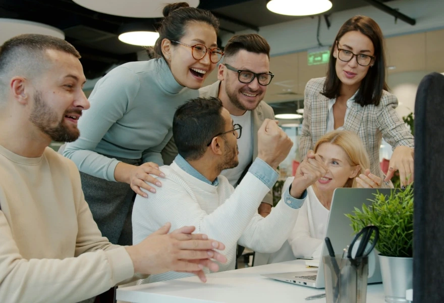 A team gathered around a computer looking happy