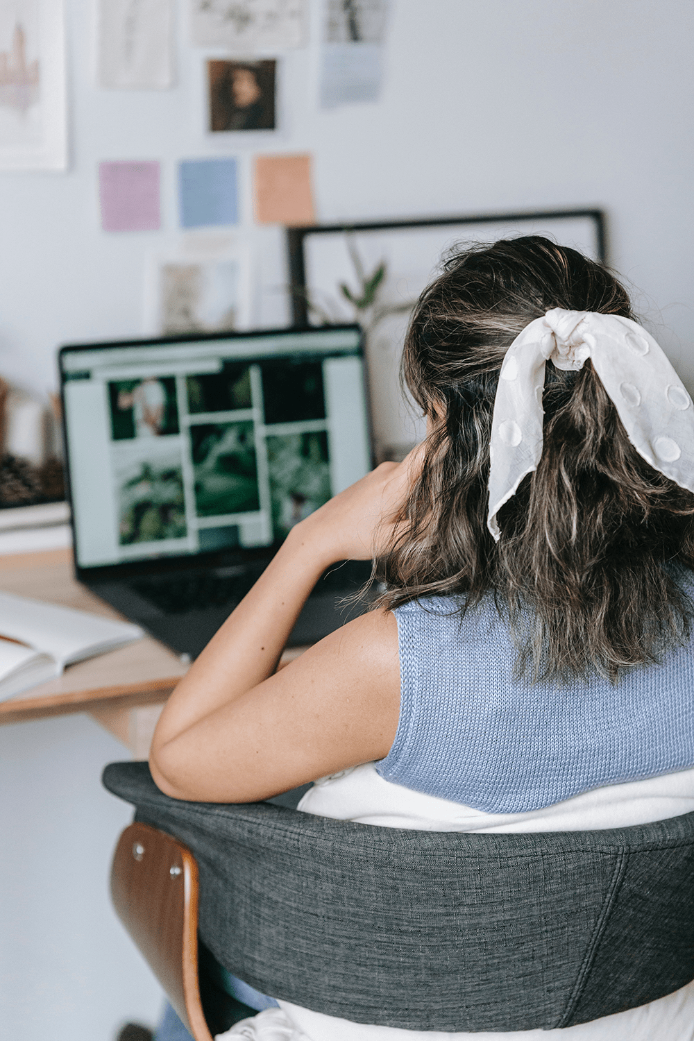 The back of a woman working with photographs on a laptop