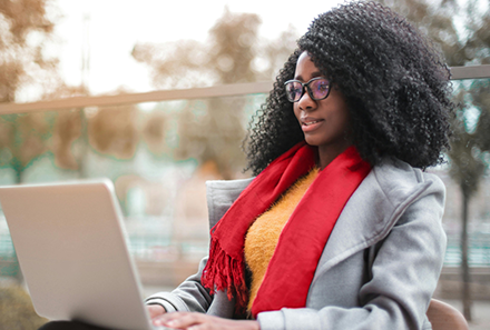 A black woman sitting outside and exploring security topics on her laptop