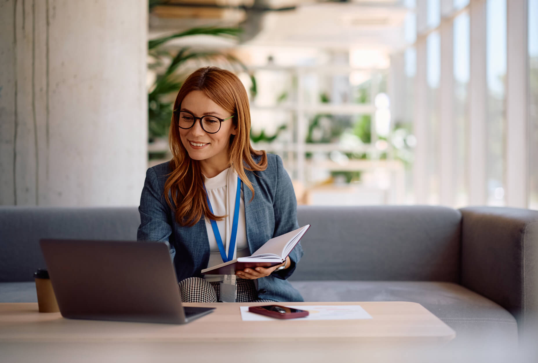 A woman sitting at a table with a laptop and a book