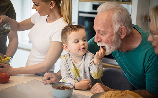 Grandson feeds grandpa snacks from a bowl