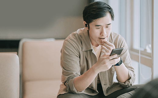 Man wearing earbuds looks at mobile phone